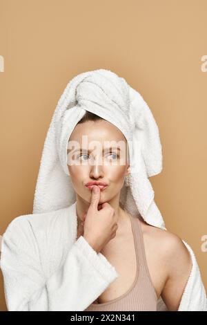 Eine Frau strahlt natürliche Schönheit aus, in ein Handtuch auf dem Kopf gehüllt, und genießt einen Moment der Selbstpflege und Entspannung. Stockfoto