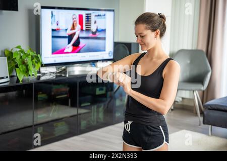 Junge Frau, die auf Fitness-Tracker blickt und Herzfrequenz, Schrittzählung und verbrannte Kalorien anzeigt. Smart Watch auf weiblicher Hand, Standpunkt, Konzept von Stockfoto