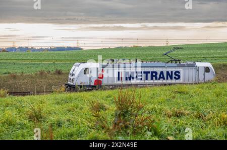 Eine Elektrolokomotive von Metrans vom Typ Bombardier Traxx AC3 zieht auf dem Bahnnetz der Deutschen Bahn einen Güterzug. (Hebertshausen, Deutschland, Stockfoto