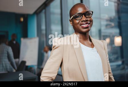 Porträt einer Geschäftsfrau in einem Sitzungszimmer. Sie steht, lächelt und blickt in die Kamera und schildert Erfolg und Professionalität. Ein reifes Fem Stockfoto