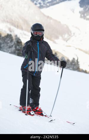 Junge Skifahrer in Skianzug und Helm stehen auf verschneiten Pisten Stockfoto