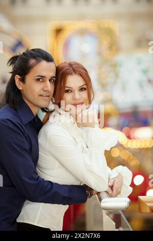 Dunkelhaariger Mann umarmen rothaarige Frau von hinten Stockfoto