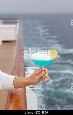 Frau Hand hält blauen Cocktail im Glas im Hintergrund des Kreuzfahrtdecks Stockfoto