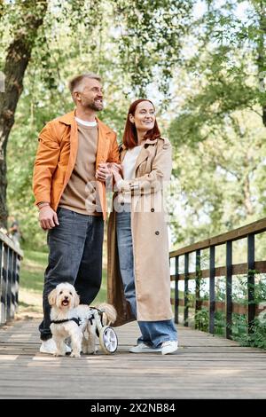 Erwachsenes Paar spaziert Hund auf Brücke im Park. Stockfoto