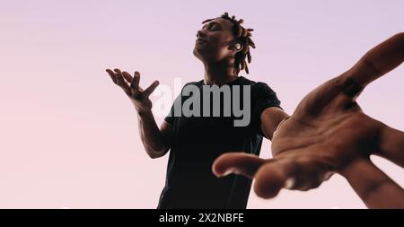 Ein Mann mit Dreadlocks tanzt energisch zu Musik, die auf seinen kabellosen Ohrstöpseln spielt. Er zeigt seine einzigartigen Tanzschritte in einem Studio, mit geschlossenen Augen Stockfoto