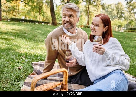 Ein Paar genießt Wein auf einer Decke im Park. Stockfoto