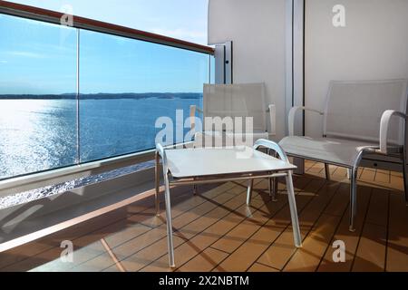 Balkon mit weißen Stühlen und Tisch auf dem Schiff mit Blick auf das blaue Meer Stockfoto