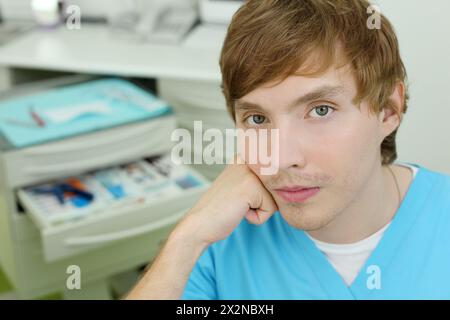 Der Zahnarzt sitzt im Schrank der Zahnklinik und schaut in die Kamera. Stockfoto