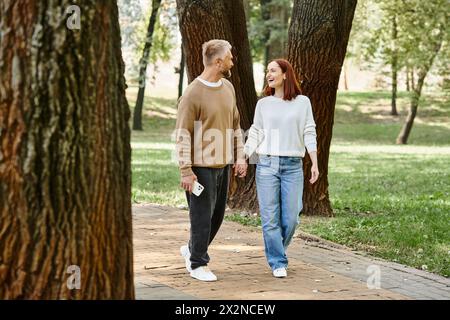 Ein Paar, lässig gekleidet, geht Hand in Hand in Hand in einen Park. Stockfoto