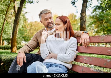 Ein Mann und eine Frau in lässiger Kleidung sitzen friedlich zusammen auf einer Parkbank. Stockfoto