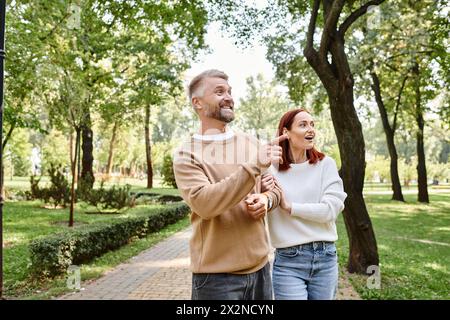 Ein Paar, lässig gekleidet, genießt einen gemütlichen Spaziergang durch einen malerischen Park. Stockfoto