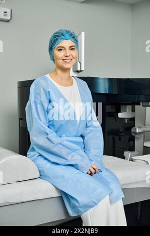 Eine Frau in einem Krankenhauskleid, die friedlich auf einem Bett sitzt. Stockfoto