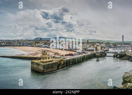 Das Bild ist von einem Blick auf den Peel Harbour Steg am Eingang zum Peel Harbour Hafen Hafen und Yachthafen mit der Strandpromenade, der Stadt Peel und Stockfoto