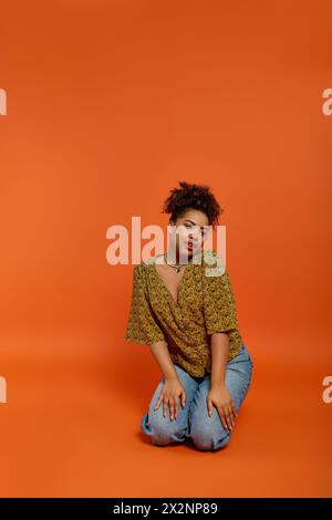 Stilvolle afroamerikanische Frau vor leuchtendem orangefarbenem Hintergrund. Stockfoto