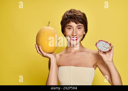 Eine junge Frau in weißem Kleid hält anmutig ein Stück Obst. Stockfoto