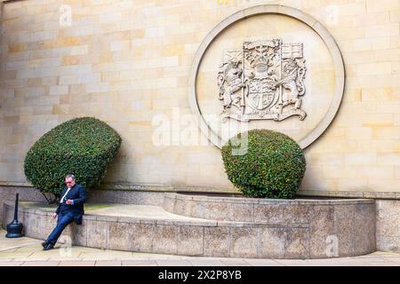 Anwältin sitzt an der Wand vor dem High Court of Justiciary, mit dem Logo des Gerichts oben, Saltmarket, Glasgow, Schottland, Großbritannien Stockfoto