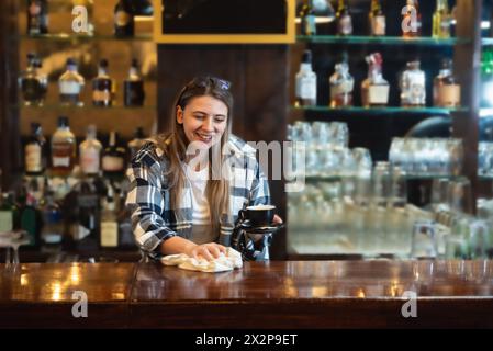 Die Kellnerin stand in der Bar und wischte und polierte das Bierglas. Die Barkeeperin arbeitet an der Bar, bereitet und putzt, arbeitet, bevor Gäste kommen, Stockfoto