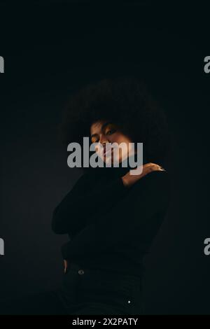 Stilvolle afroamerikanische Frau steht im Dunkeln. Stockfoto