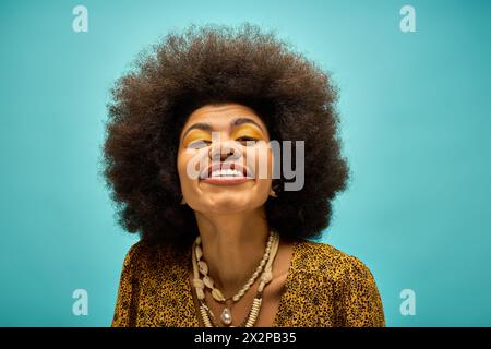 Eine stilvolle afroamerikanische Frau in trendiger Kleidung, mit einem strahlenden Lächeln und einem üppigen Afro. Stockfoto