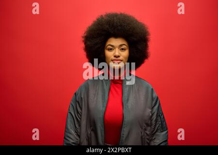 Stilvolle afroamerikanische Frau mit lockigen Frisuren vor leuchtend rotem Hintergrund. Stockfoto