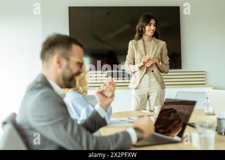 Die kompetente Frau präsentiert sich während eines Meetings vor Kollegen, wobei ihr Ausdruck Begeisterung und Führungsstärke zum Ausdruck bringt Stockfoto