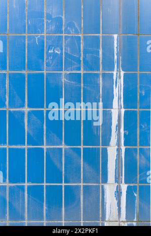 Blaue Keramikfliesenwand mit Farbspritzern Stockfoto