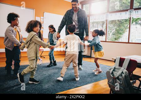 Spaß in der Grundschule. Der Lehrer spielt ein Spiel mit seinen Schülern in einem Klassenzimmer. Spaß ist ein Teil der frühen kindlichen Entwicklung. Stockfoto