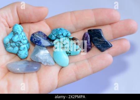 Die junge Frau hält eine Sammlung verschiedener roher Edelsteine in der Hand Stockfoto