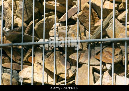 Gabion. Zaun aus Stein und Draht, Nahaufnahme. Moderner Zierzaun. Stockfoto