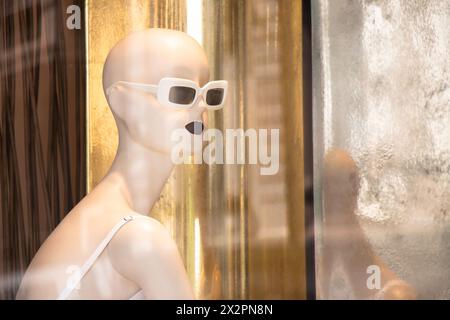 Belgrad, Serbien - 3. April 2024: Unscharfe Mannequin-Modepuppen in weißem Kleid mit goldenen Reflexen im Schaufenster des Max Mara-Geschäfts Stockfoto