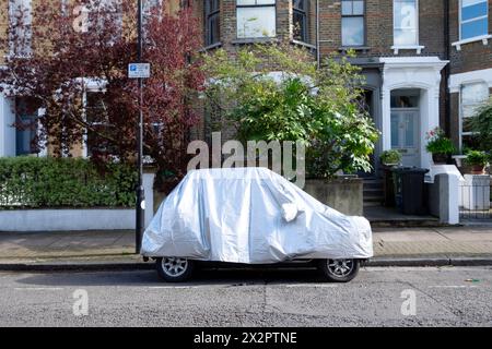 Kleines Auto mit silberner Schutzabdeckung, geparkt vor dem Haus auf der Straße in Clapton London England Großbritannien KATHY DEWITT Stockfoto