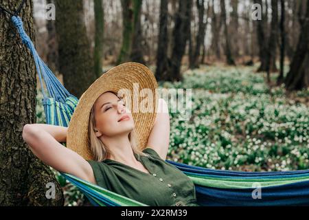 Sorglose Frau mit geschlossenen Augen, die sich in der Hängematte im Wald entspannt Stockfoto