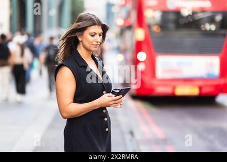 Eine junge Frau, die auf der Straße ein Handy benutzt Stockfoto