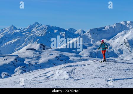 Reife Frau im Langlauf auf dem Kastenwendenkopf mit Zillertaler Alpen im Hintergrund am sonnigen Tag, Kitzbühel Alpen, Tirol, Österreich Stockfoto