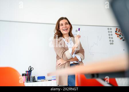 Glückliche Geschäftsfrau mit Filzstift vor dem Whiteboard Stockfoto