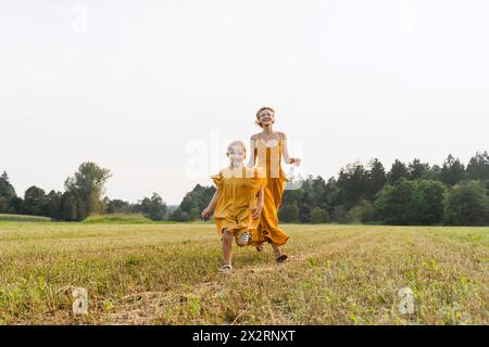 Verspielte Mutter und Tochter laufen auf der Wiese Stockfoto