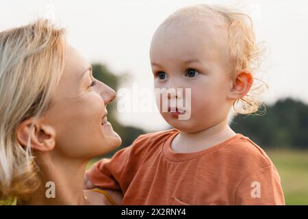 Nachdenklicher Junge mit lächelnder Mutter auf der Wiese Stockfoto