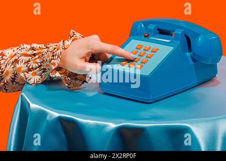 Frau, die am Telefon die Nummer vor orangefarbenem Hintergrund wählt Stockfoto