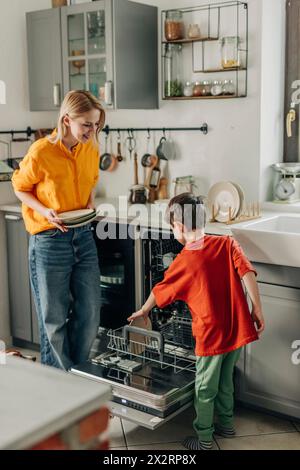 Sohn hilft Mutter beim Geschirrwaschen zu Hause Stockfoto