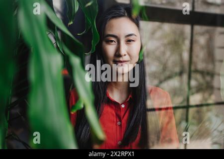 Eine junge Frau hat durch ein Glasfenster fotografiert Stockfoto