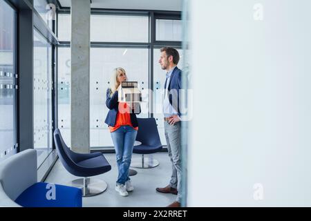Architekt hält Modellhaus und diskutiert mit Kollegen im Büro Stockfoto