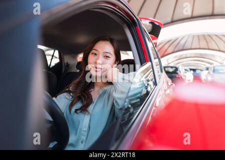 Lächelnde junge Frau sitzt im Auto Stockfoto