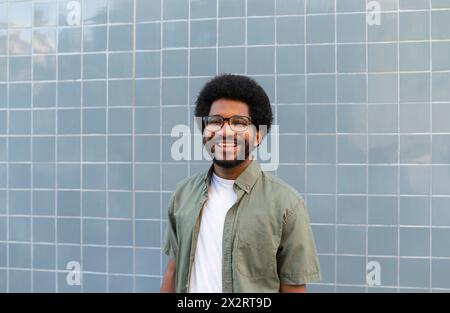 Lächelnder junger Mann, der vor einer gekachelten Wand steht Stockfoto