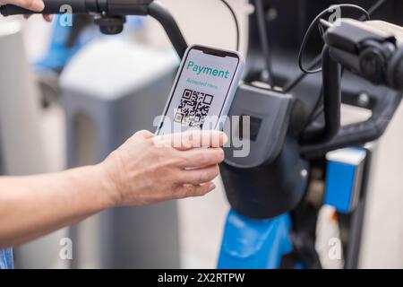 Hände einer Frau, die für Fahrradverleih über das Smartphone bezahlt Stockfoto