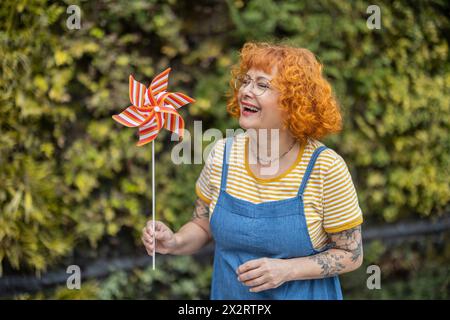 Glückliche rothaarige Frau mit Windradspielzeug Stockfoto