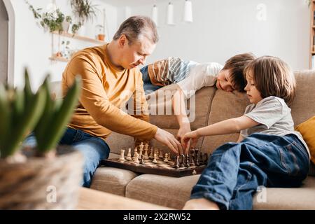 Familie spielt Schach auf Sofa zu Hause Stockfoto