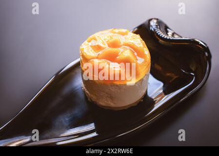 Soufflé-Kuchen mit Mangobart auf einem Teller aus einer Weinflasche auf dunklem Hintergrund Stockfoto