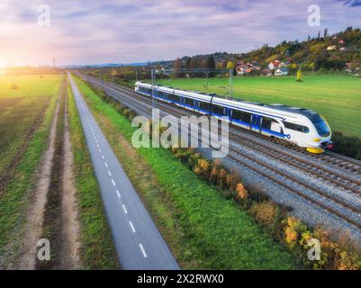Blick aus der Vogelperspektive auf Hochgeschwindigkeitszüge, Berge, grüne Felder, Straße Stockfoto