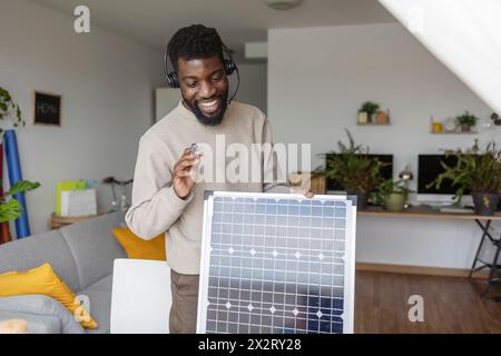 Glücklicher Freelancer, der ein Headset trägt und zu Hause über Solarmodule spricht Stockfoto