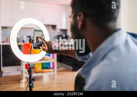 Influencer mit Smartphone an Ringlicht zu Hause Stockfoto